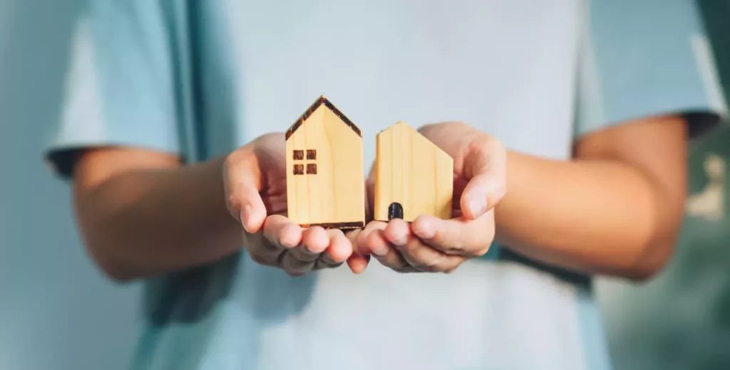 hands holding wooden house